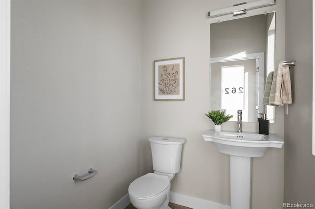 half bathroom featuring toilet and baseboards