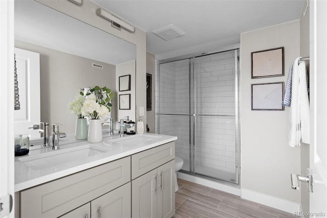full bath featuring visible vents, a sink, a shower stall, and double vanity
