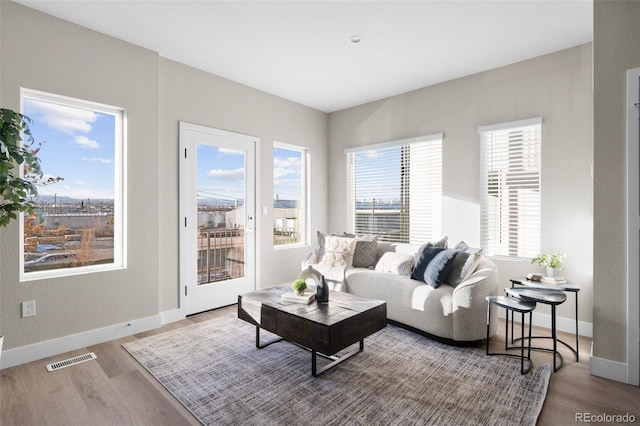 living area featuring baseboards, wood finished floors, and visible vents