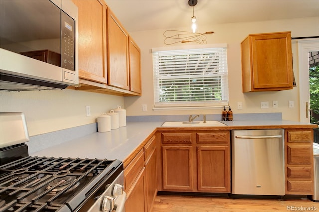 12671 Meadow Bridge Way, Parker, CO 80134 - kitchen with appliances with stainless steel finishes, a sink, light countertops, light wood-type flooring, and brown cabinetry