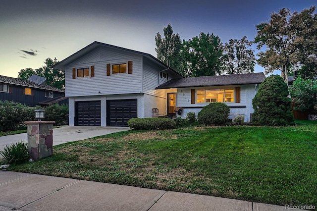 split level home featuring brick siding, a front lawn, an attached garage, and driveway