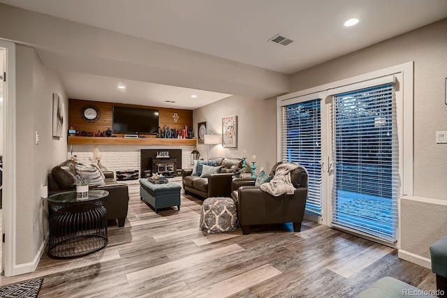 living area with a brick fireplace, recessed lighting, baseboards, and wood finished floors