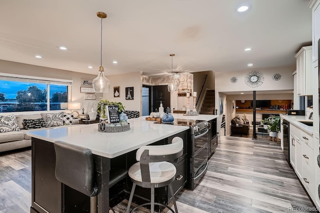 kitchen with electric range, a spacious island, recessed lighting, white cabinets, and light wood finished floors