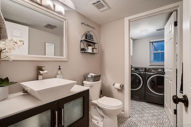 bathroom featuring a textured ceiling, visible vents, toilet, a textured wall, and washer and dryer