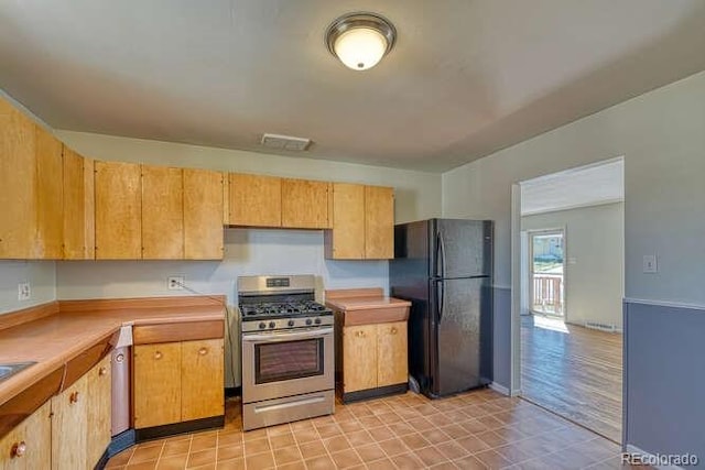 kitchen featuring light wood-type flooring, stainless steel gas range, and black refrigerator