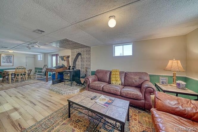 living room featuring a textured ceiling, hardwood / wood-style floors, a wood stove, and a wealth of natural light