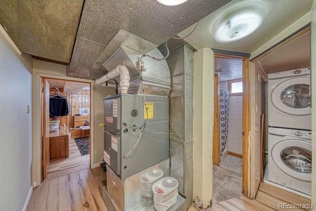 laundry area with light hardwood / wood-style flooring and stacked washer and dryer