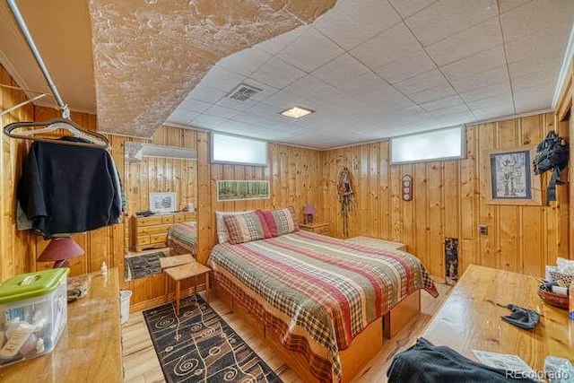 bedroom featuring wooden walls and light hardwood / wood-style floors