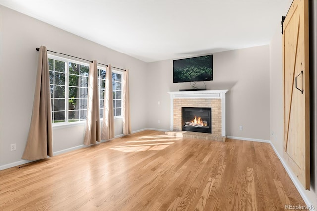 9898 Tourmaline Ct, Parker, CO 80134 - unfurnished living room featuring light wood-style flooring, a brick fireplace, and baseboards