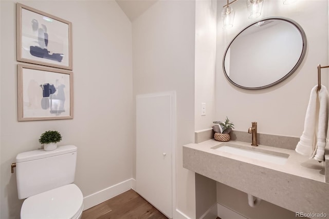 bathroom featuring hardwood / wood-style floors, toilet, lofted ceiling, and sink