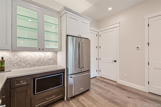 kitchen with white cabinets, high end refrigerator, light wood-type flooring, and tasteful backsplash