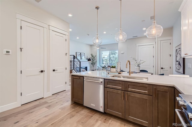 kitchen featuring stainless steel appliances, ceiling fan, sink, light hardwood / wood-style floors, and hanging light fixtures