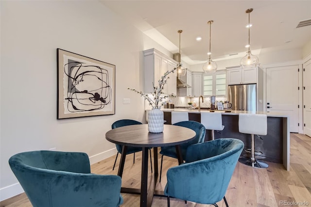 dining space featuring light wood-type flooring and sink