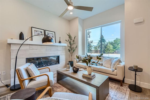 living room featuring a tile fireplace, ceiling fan, and hardwood / wood-style floors