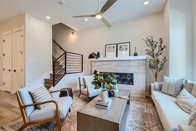 living room featuring ceiling fan, light wood-type flooring, and a tile fireplace