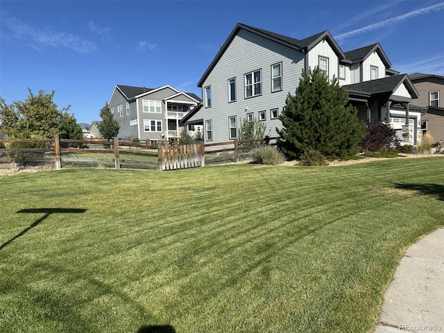 back of property featuring a yard, fence, board and batten siding, and a residential view