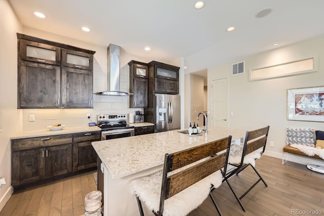19 S 45th Ave, Brighton, CO 80601 - kitchen with a kitchen breakfast bar, wall chimney range hood, light wood-type flooring, a sink, and appliances with stainless steel finishes