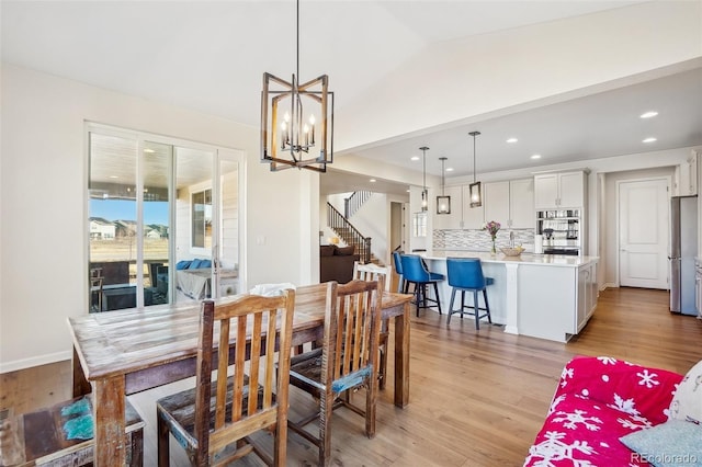 dining room with vaulted ceiling, a chandelier, and light hardwood / wood-style floors