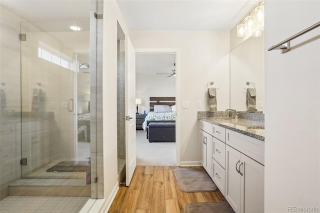 bathroom featuring hardwood / wood-style flooring, vanity, a shower with door, and ceiling fan