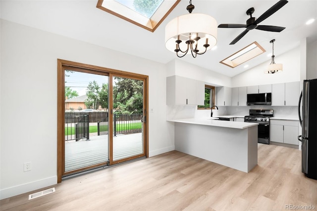 655 Cree Cir, Boulder, CO 80303 - kitchen featuring a skylight, stainless steel gas stove, black microwave, freestanding refrigerator, and a peninsula