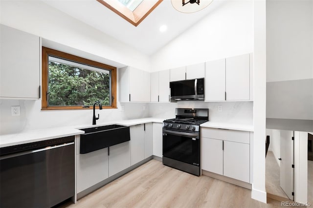 655 Cree Cir, Boulder, CO 80303 - kitchen featuring appliances with stainless steel finishes, a skylight, lofted ceiling, light countertops, and light wood-style floors