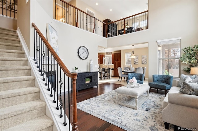 living room featuring wood-type flooring, stairway, baseboards, and recessed lighting