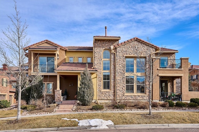 view of front of property featuring a balcony, stone siding, and stucco siding