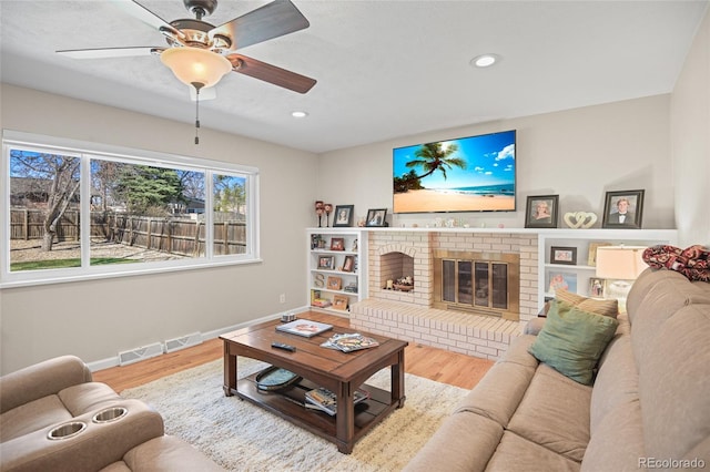 living room featuring hardwood / wood-style floors, a brick fireplace, and ceiling fan