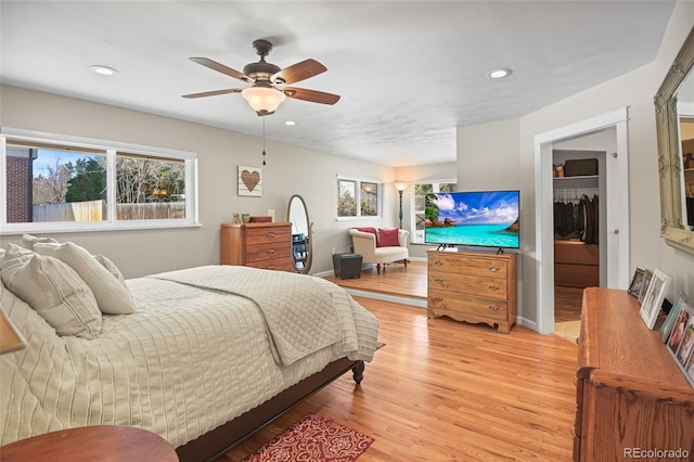 bedroom with ceiling fan, light hardwood / wood-style floors, a closet, and multiple windows