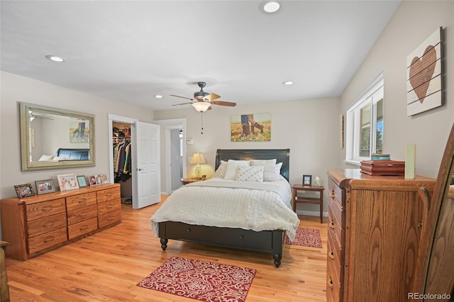 bedroom with a walk in closet, ceiling fan, a closet, and light hardwood / wood-style floors