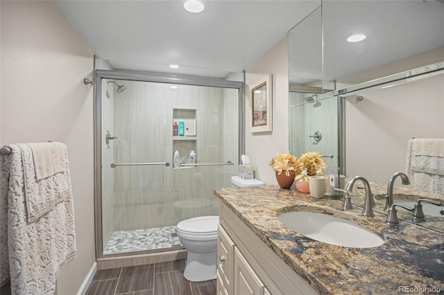 bathroom with vanity, toilet, and a shower with door