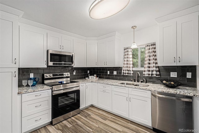 3715 Manchester St, Colorado Springs, CO 80907 - kitchen featuring stainless steel appliances, a sink, white cabinets, backsplash, and light wood-style flooring
