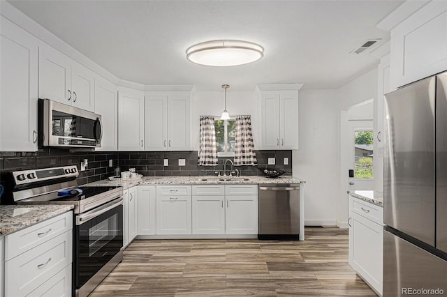 3715 Manchester St, Colorado Springs, CO 80907 - kitchen featuring stainless steel appliances, a sink, decorative backsplash, light wood-style floors, and white cabinetry
