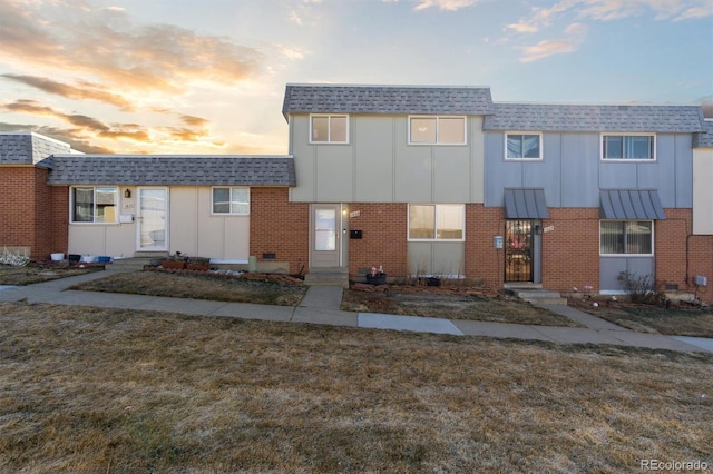 townhome / multi-family property with brick siding, board and batten siding, and a shingled roof