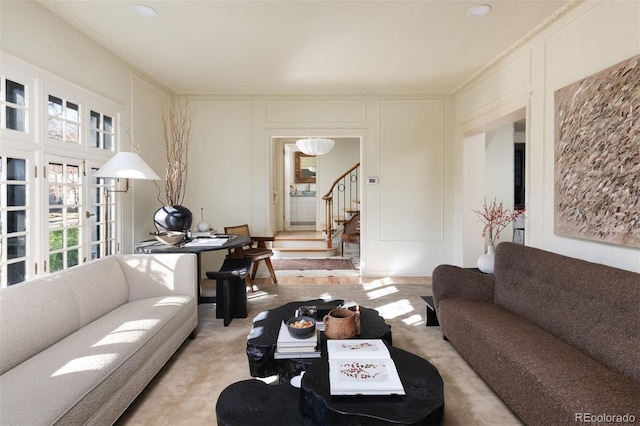 living area featuring stairs, carpet flooring, and a decorative wall