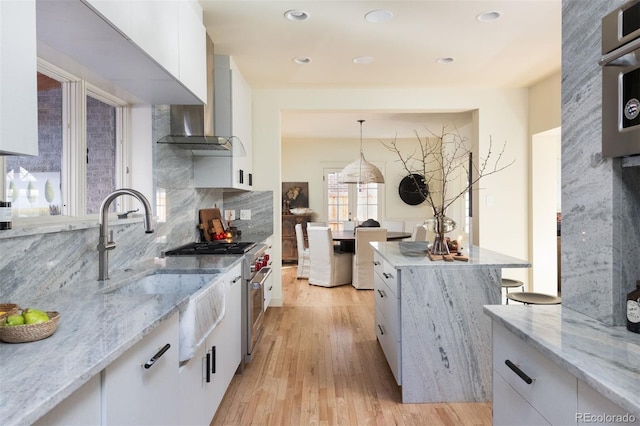 kitchen featuring light stone counters, light wood finished floors, tasteful backsplash, white cabinets, and modern cabinets