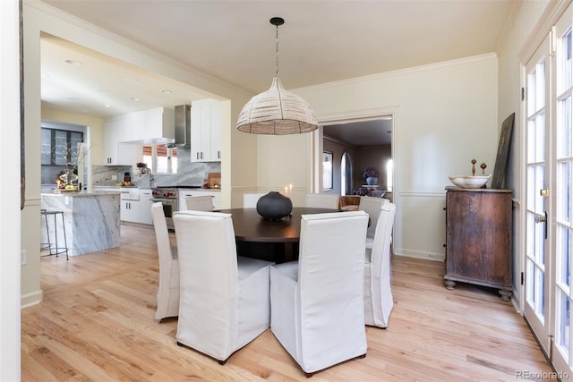 dining space with crown molding, a wealth of natural light, and light wood-style floors