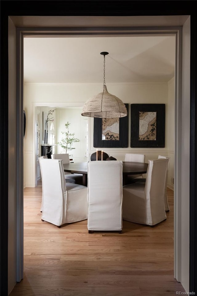 dining area with crown molding and light wood-style floors