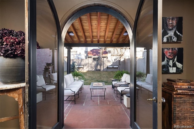 exterior space featuring wood ceiling, stone tile floors, arched walkways, and beamed ceiling