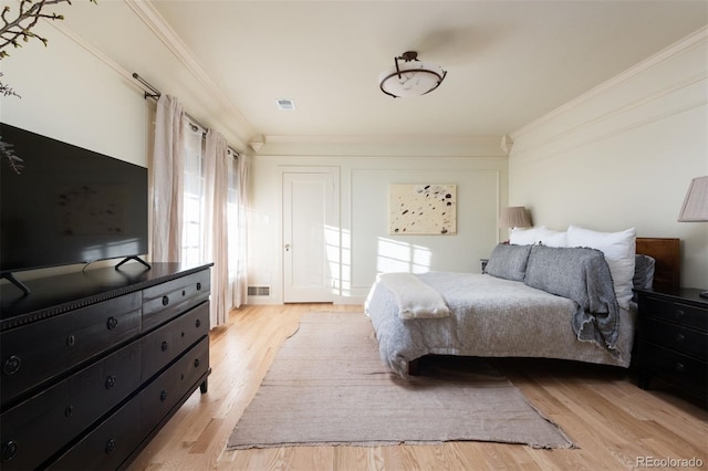 bedroom with light wood finished floors, ornamental molding, and visible vents