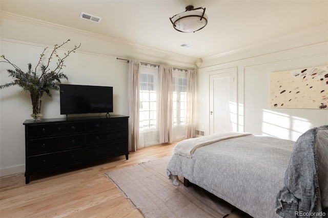 bedroom featuring visible vents, light wood-style flooring, and crown molding