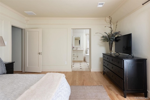 bedroom with visible vents, ensuite bathroom, light wood-style floors, ornamental molding, and a sink