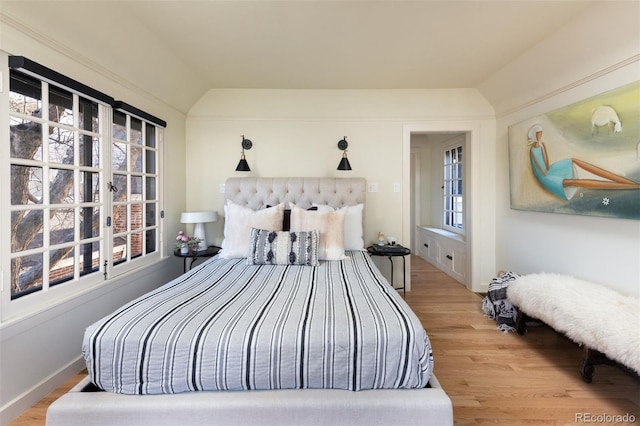 bedroom featuring lofted ceiling, multiple windows, and wood finished floors