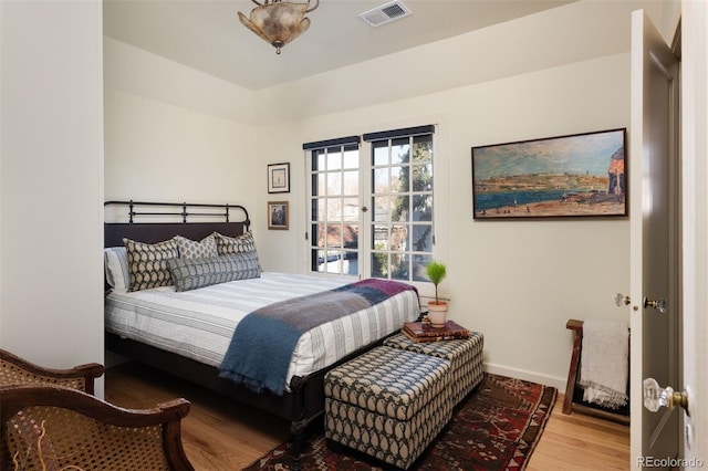 bedroom with wood finished floors, visible vents, and baseboards