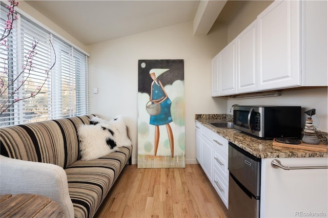 kitchen with stainless steel microwave, light wood-style floors, white cabinetry, vaulted ceiling, and dishwashing machine