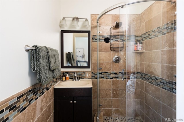 bathroom with a stall shower, tile walls, and vanity