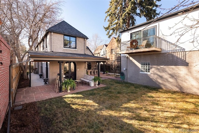 back of property featuring brick siding, fence, a lawn, and a patio