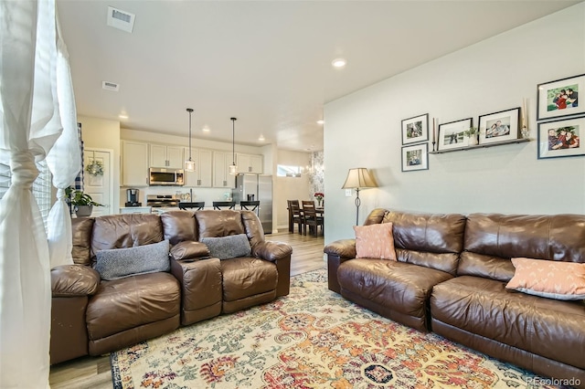 living room with an inviting chandelier, light hardwood / wood-style floors, and plenty of natural light