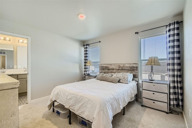 carpeted bedroom with connected bathroom and sink