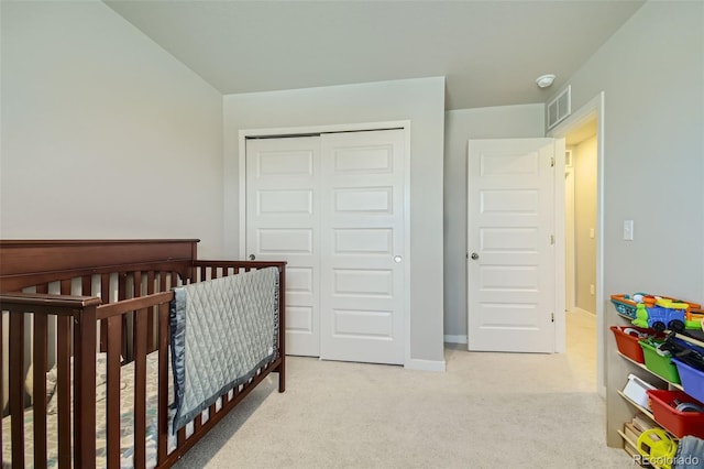 bedroom featuring light carpet, a nursery area, and a closet